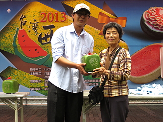造型西瓜冠軍得主雲林縣二崙鄉廖文斌頒贈一粒方型西瓜給現場模彩幸運得主